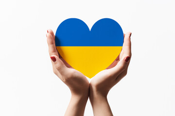Women hands holding ukraine flag color heart shape paper on white background