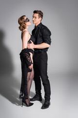 full length of man and erotic woman in mask and lingerie on grey background.