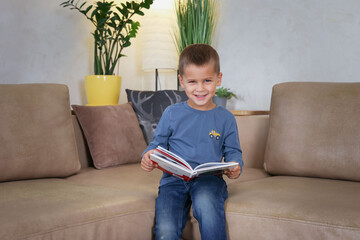 baby looks at the camera and holds a book in his hands. High quality photo