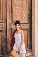 Fototapeta premium Caucasian young woman posing near the wooden door and looking away