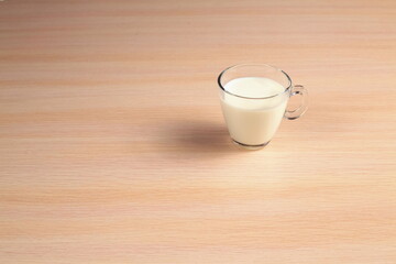 Transparent glass cup with milk on a wooden table