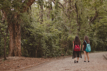 two teenager girl friends walking in nature with backpacks