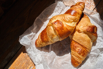 Freshly baked croissant shiny in the rays of the morning sun. Fresh homemade cakes. Delicious traditional french crispy croissants for breakfast

