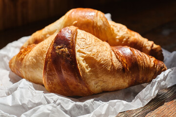 Freshly baked croissant shiny in the rays of the morning sun. Fresh homemade cakes. Delicious traditional french crispy croissants for breakfast

