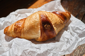 Freshly baked croissant shiny in the rays of the morning sun. Fresh homemade cakes. Delicious traditional french crispy croissants for breakfast