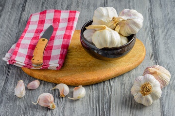 some garlic in a bowl with a kitchen towel and a knife.