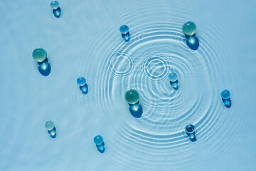 Abstract background, texture of blue water with round ripples with transparent balls, capsules