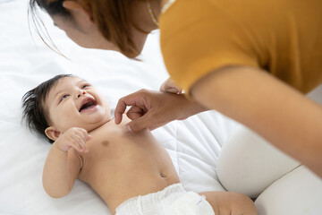 mother changing diaper a newborn baby lying on the bed