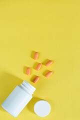 Pills and pill bottles on yellow background,Multicolor tablets and pills capsules from glass bottle on yellow background Heap of assorted various medicine tablets and pills. Health care Close-up Copy 