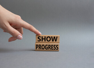 Progress symbol. Wooden blocks with words Show progress. Beautiful grey background. Businessman hand. Business and 'Show progress' concept. Copy space.