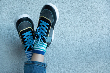 Kid wearing different pair of socks. Child legs up in mismatched socks on gray background. Odd...