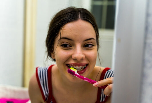 A Girl Is Brushing Her Teeth And Teeth Braces With A Special Brush During The Day In Her Bathroom