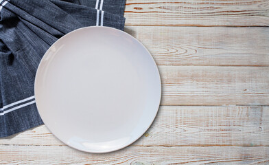 Empty white plate and napkin on light grey table, flat lay