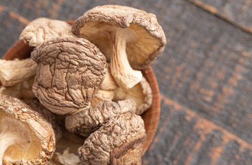 A Bowl of Whole Dried Shiitake Mushrooms on a Wooden Table
