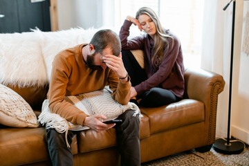 An Unhappy Couple Sit Together on a Couch 