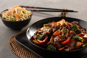 beef with broccoli and stir-fry noodles served in dish isolated on dark background side view
