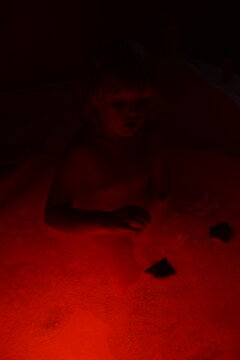 A little child taking a bath in a dark