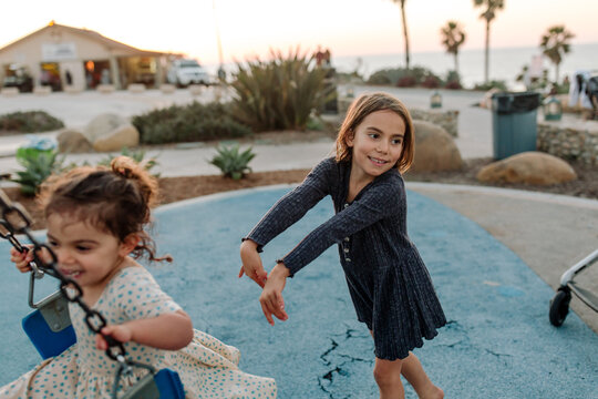 Happy girl pushing sister on swing