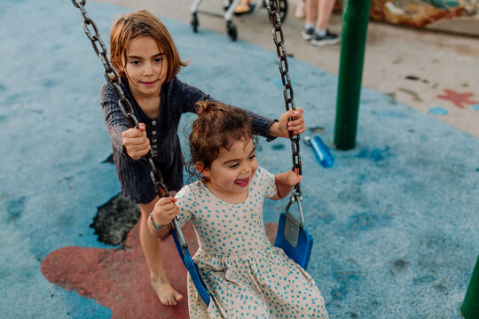 Sister pushing young girl on swing