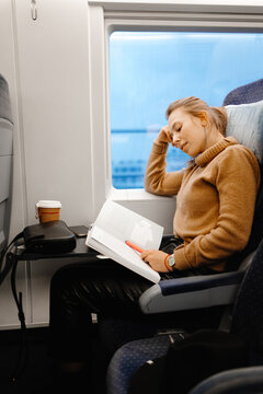 Attractive female passenger reading book in railway transport 