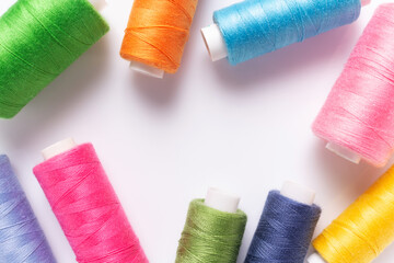 Bright sewing thread spool at white background, top view. Colorful spool with thread