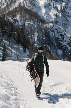 Active person carrying snowboard in mountains