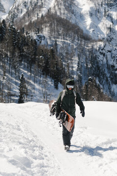 Active person carrying snowboard in mountains