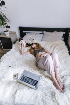 Girl relaxing in cozy bedroom while touching muzzle of kitty