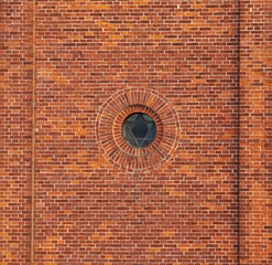 Wall of a jewish synagogue with round window on an old red brick house outside. Small metal frame...