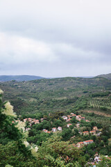 Fototapeta na wymiar Top view of a European village in the green hills. Italian houses with red roofs, orchards in the valleys, and rich greenery.