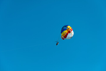 Happy couple parasailing on the beach in summer. A couple under a parachute hangs in the air. Tropical paradise. Positive human emotions, feelings, family, travel, vacation.