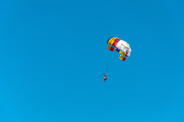 Happy couple parasailing on the beach in summer. A couple under a parachute hangs in the air. Tropical paradise. Positive human emotions, feelings, family, travel, vacation.