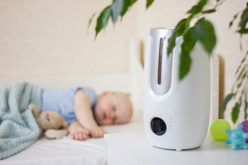Cute little baby boy sleeping in bedroom with air humidifier.