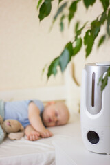 Cute little baby boy sleeping in bedroom with air humidifier.