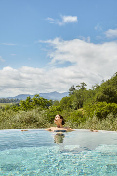 Woman soaking in hot tub pool on vacation at luxury resort and spa