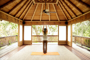 Woman doing yoga in Japanese yoga deck pavilion