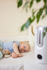 Cute little baby boy sleeping in bedroom with air humidifier.