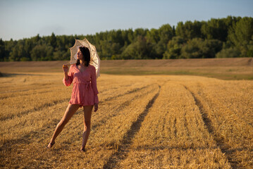 Beautiful young woman with parasol walking in the nature on a sunny summer day