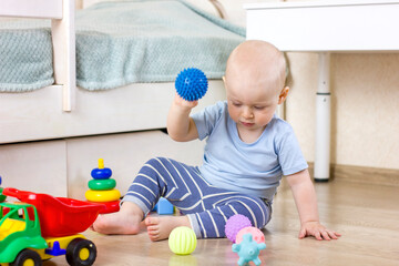 Cute baby boy toddler playing with massage balls.