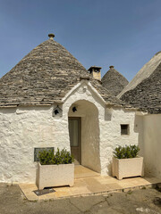 Fototapeta na wymiar Alberobello, Italy, Apulia region Trullo buildings, Trulli of Alberobello UNESCO, trullo detailed with horizontal stone conical roof and front entrance flanked by potted plants