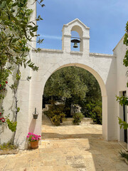 Alberobello, Italy, Apulia region whitewashed archway leading into a garden with olive trees