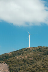 Fototapeta na wymiar a wind turbine on a monatia, in the background of the blue sky