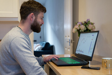 Man smiling whilst checking finance and share  portfolio at home