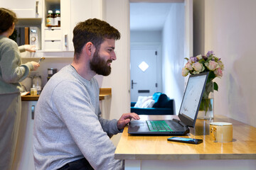 Young couple at home, man working at kitchen table