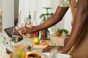 Unrecognizable mixologist using tablet at workspace