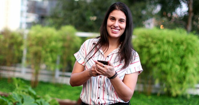 Happy young woman celebrates after good news holding cellphone