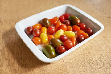 Food stuff. Closeup of roma or cherry tomatoes in a glass bowl served on a wooden table for diet, healthy salads and nutrition. Fresh, organic fruit farmed in home garden or agriculture farm.