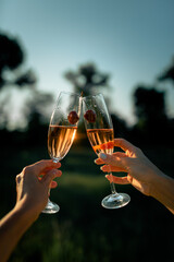 Two glasses of champagne in female hands in the sunset