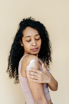 Mixed race female smearing cream on arm