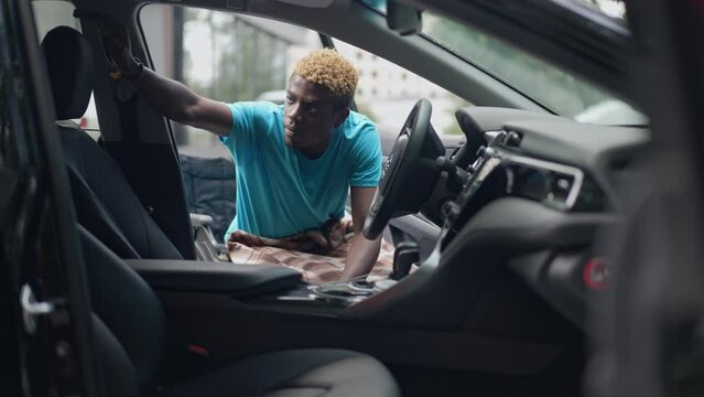 Shooting from car of African American man in wheelchair entering vehicle in slow motion. Handsome young ill guy fighting challenge at automobile outdoors